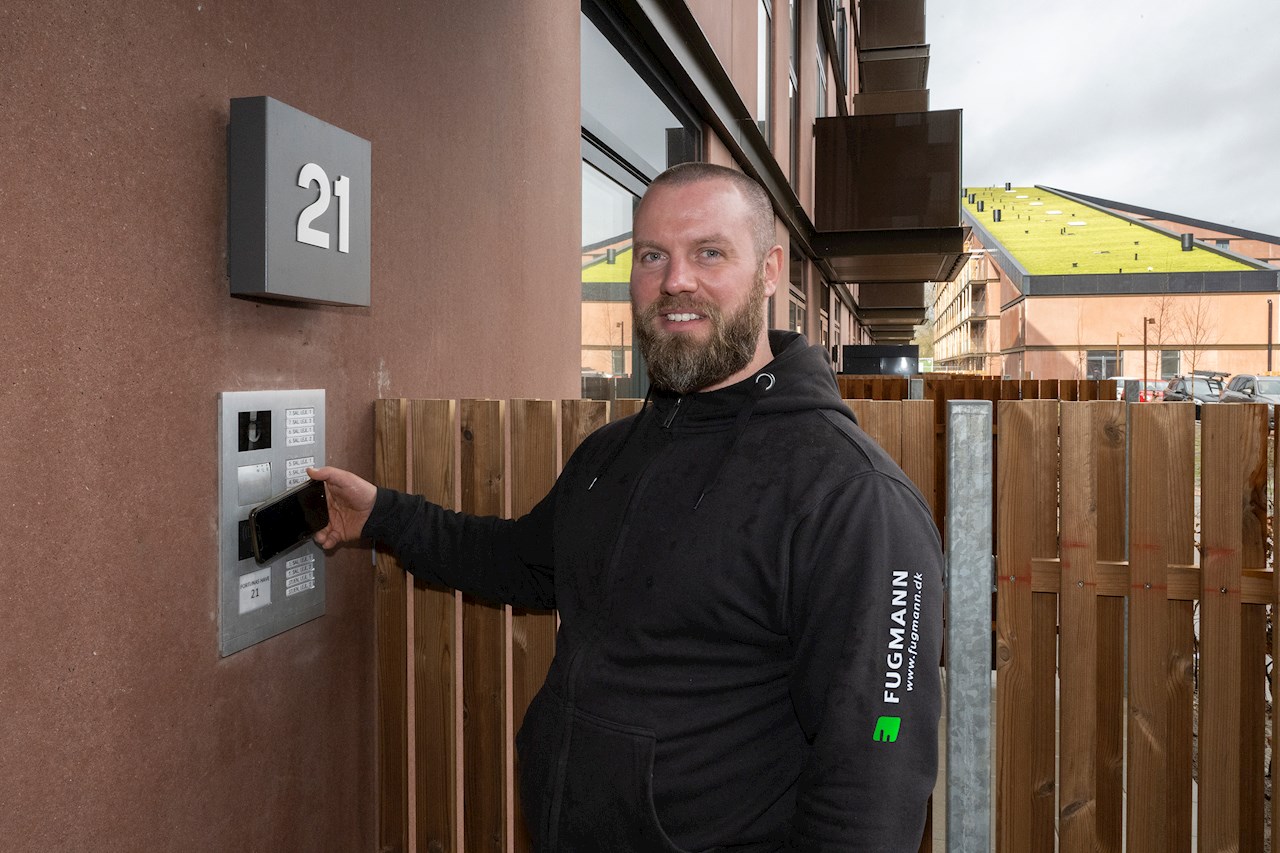 Formand Peter Andersen fra Fugmann A/S viser, hvordan gadedøren kan låses op med mobiltelefonen, som man holder op mod ABB's dørtelefon.